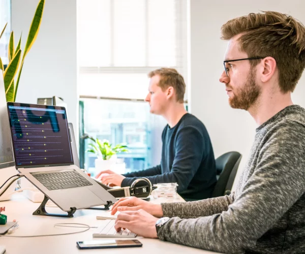 Deux collaborateurs en train de travailler devant leurs ordinateurs.